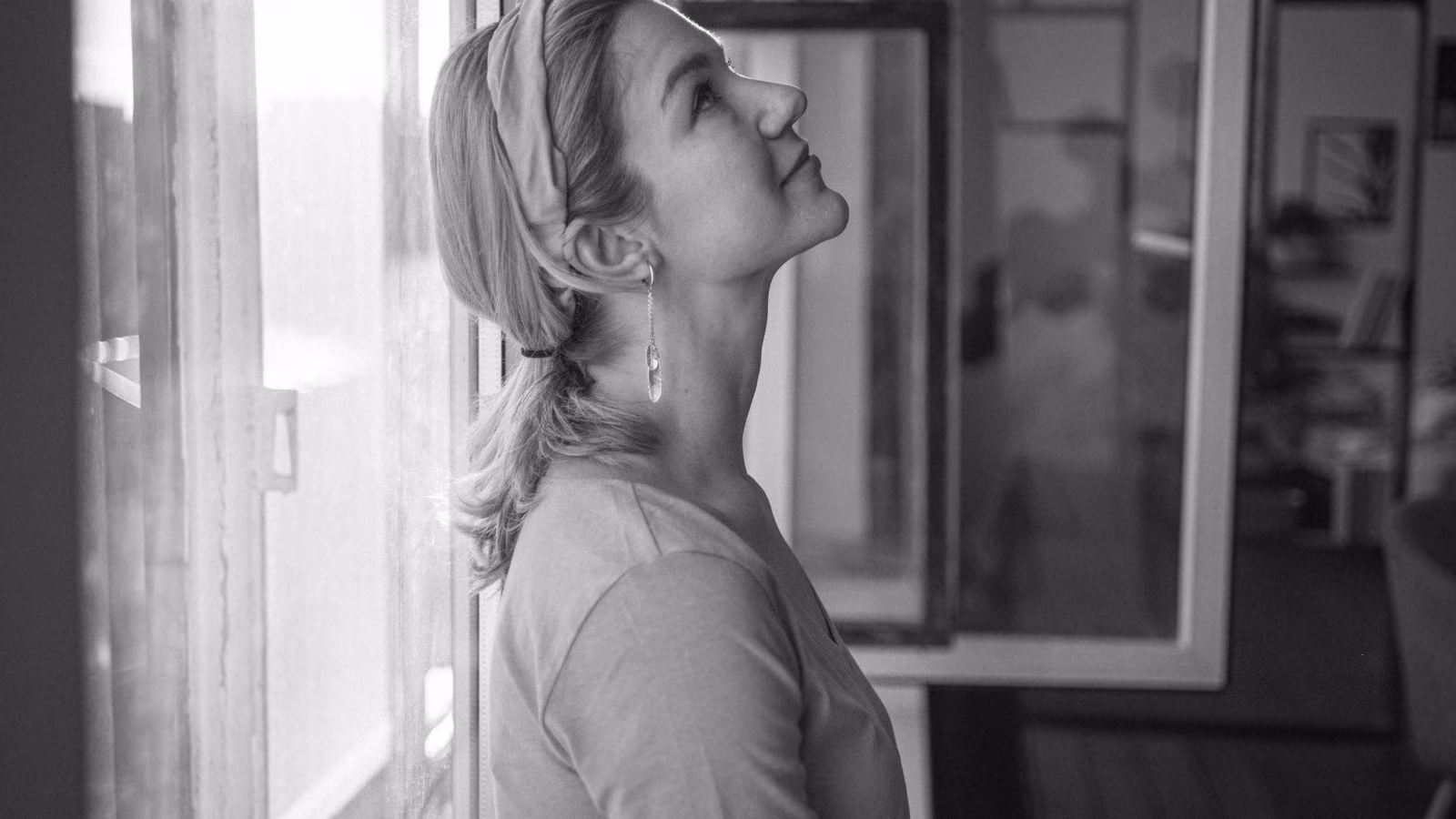 A woman pausing to look out a window, taking a quiet moment to herself